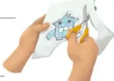 Manos recortando con tijeras un dibujado de monstruo.