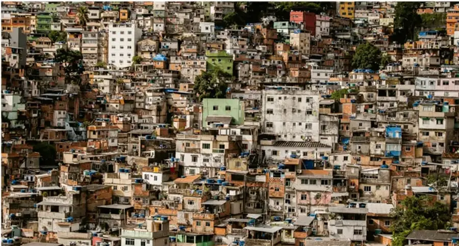 Fotografía aérea de un conjunto urbano denso de viviendas populares construidas en una ladera, con edificios de distintos colores y alturas, ilustrando la construcción de vivienda a gran escala.