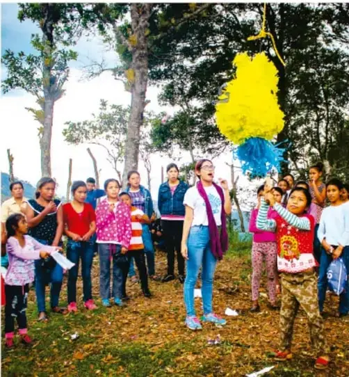 Fotografía de un grupo de mujeres y niñas en un espacio al aire libre, participando en una actividad comunitaria con objetos de colores amarillo y azul, ilustrando el trabajo colectivo.