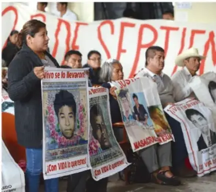 Fotografía de una protesta con personas sosteniendo carteles con la frase 'Vivo se lo llevaron' y rostros de los normalistas desaparecidos.