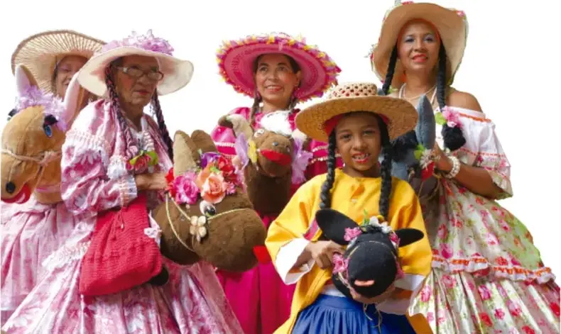 Fotografía de un grupo de mujeres con vestimenta tradicional de colores vivos y sombreros, algunas con trenzas y accesorios florales, que representan la diversidad cultural.