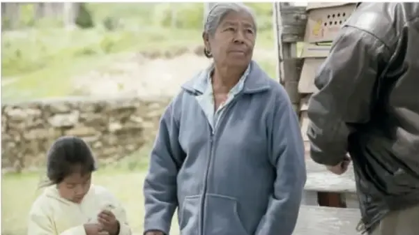 Fotograma del cortometraje: una mujer mayor con una niña y un hombre de espaldas.