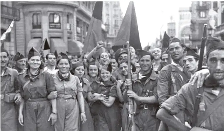 Fotografía en blanco y negro de un grupo de milicianos, hombres y mujeres, con armas y banderas, marchando por una calle.
