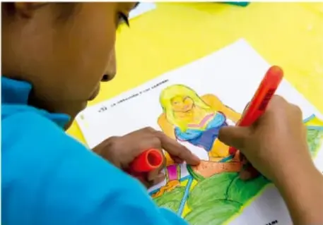 Niño coloreando un dibujo sobre una hoja blanca.