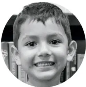Fotografía circular en blanco y negro de un niño sonriente de primaria.