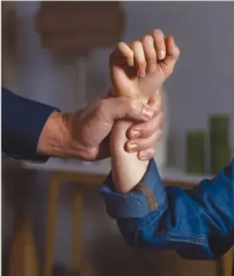 Dos manos entrelazadas con fuerza, una de ellas sujetando la muñeca de la otra, simbolizando la violencia sexual y la falta de consentimiento.