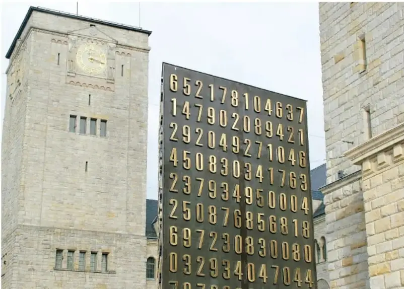 Fotografía de una torre con reloj y un panel con números grandes, relacionada con códigos y cifrados.
