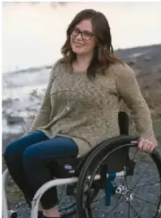Sofía, mujer joven con lentes que usa silla de ruedas en un entorno natural.