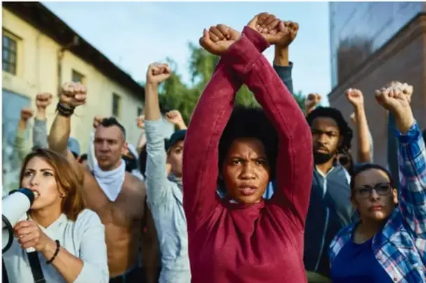 Grupo diverso de personas con los puños levantados en señal de protesta o reivindicación de derechos.