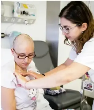 Fotografía de una joven adolescente en una consulta médica con una profesional de salud que le revisa el cuello.