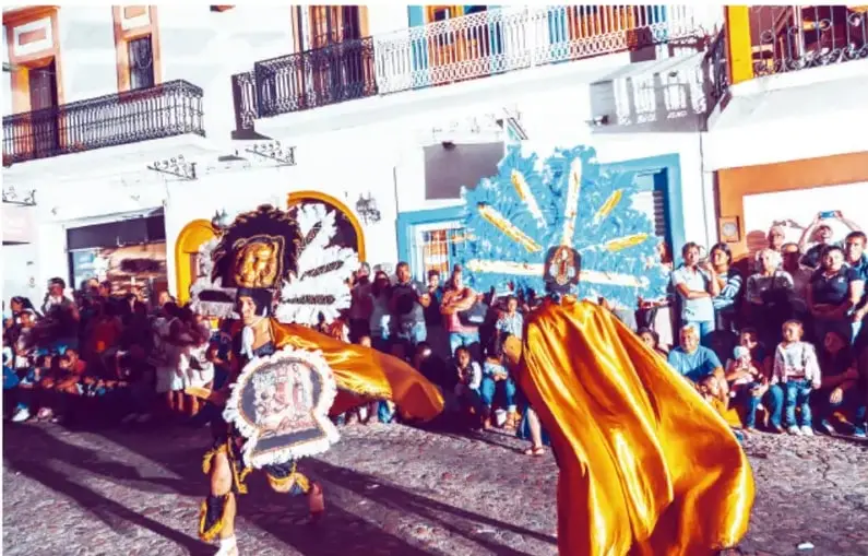 Fotografía de una celebración comunitaria con personas disfrazadas y público en una calle.