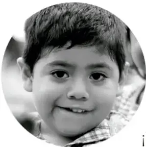 Fotografía circular en blanco y negro de un niño sonriente, probablemente estudiante de primaria.