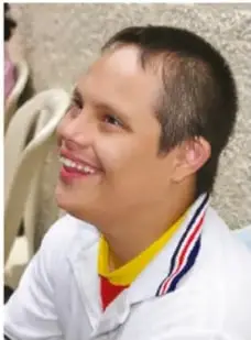 Pablo, joven con síndrome de Down que sonríe y viste uniforme deportivo con banda.