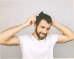 Fotografía de un hombre con camisa blanca que se mesa el cabello con ambas manos, con expresión graciosa. Ilustra el concepto de verbo reflexivo (a) con el ejemplo 'Yo me peino'. Crédito: Shutterstock (2020) 1192766260.