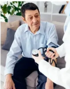 Persona mayor recibiendo atención de salud (toma de presión arterial) en un consultorio.