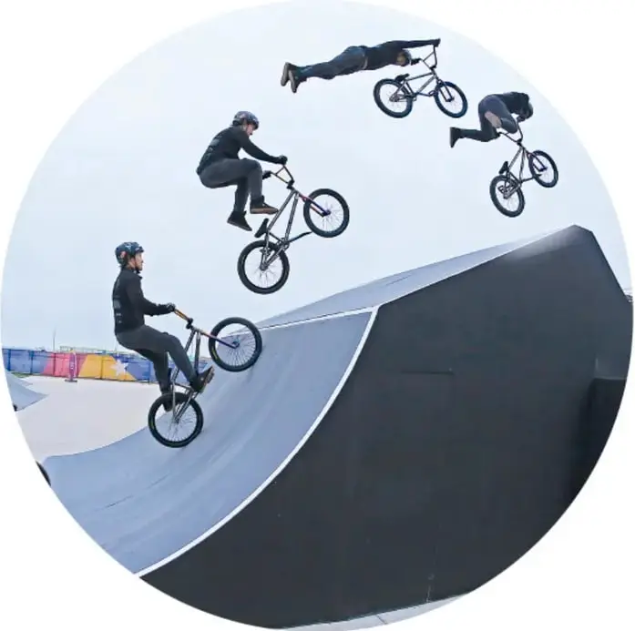 Cuatro ciclistas de BMX realizan saltos y acrobacias sobre una rampa. Uno de ellos está en el aire con la bicicleta extendida.