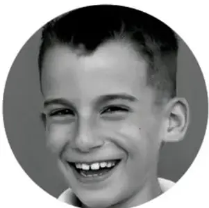 Fotografía de un niño sonriente con camisa blanca.