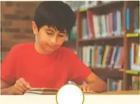 Un niño escribe mientras está sentado junto a una mesa.