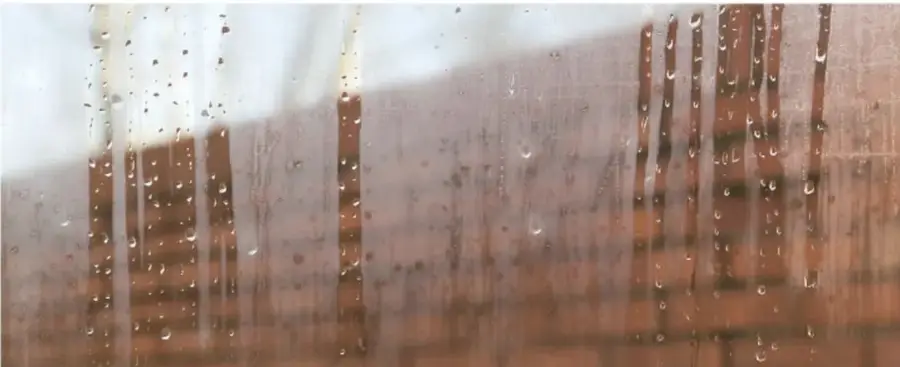 Fotografía de gotas de agua sobre un vidrio o superficie, con fondo de tonos cálidos.