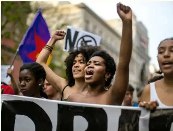 Fotografía de una protesta contra el racismo con personas levantando el puño y una pancarta.
