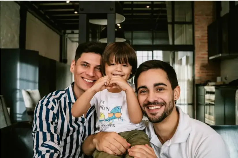 Fotografía de un adulto y un niño sonriendo y abrazados en un ambiente interior, representando el afecto familiar.