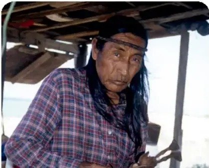 Hombre comcáac (seri) con vestimenta tradicional, en un espacio de trabajo artesanal.