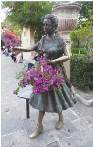 Estatua de bronce del sereno: hombre con sombrero, manta y bastón que camina de noche alzando la mano con una linterna o farol.