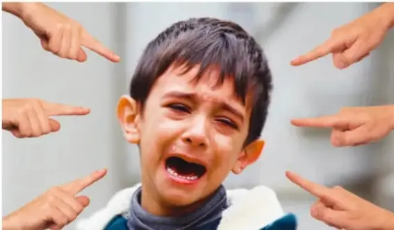 Fotografía de un niño que llora mientras varias manos entran al cuadro señalándolo con el dedo, ilustrando el acoso, la exclusión o la discriminación.