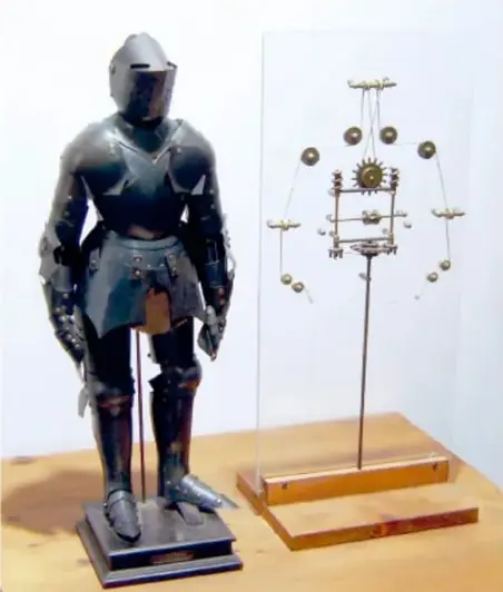 Fotografía de una réplica del Automa cavaliere: armadura metálica de caballero sobre una base, junto a un esquema de su mecanismo interno de poleas y engranajes.