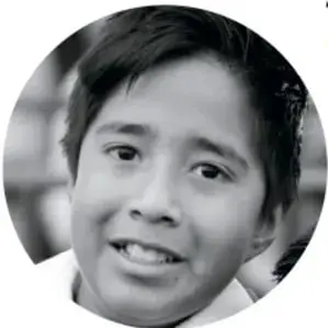 Fotografía de un niño sonriente con camisa blanca, mirando a la cámara.