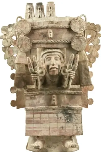 Escultura de Xilonen: figura con estructura arquitectónica en forma de templo o granero con flores/rosetas y una figura central sosteniendo mazorcas o mazorcas en las manos.