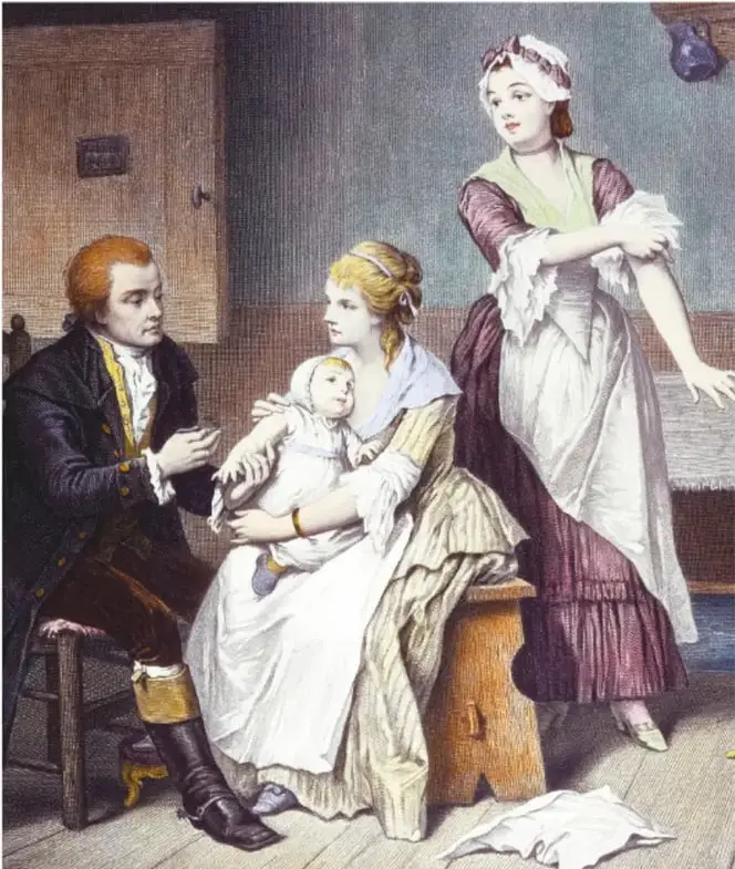 Grabado histórico coloreado: el médico Edward Jenner, sentado con levita oscura, examina a un bebé que sostiene una madre sentada en un banquillo; detrás, la joven Sarah Nelmes muestra su brazo con la manga recogida; escena del siglo XVIII.