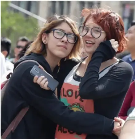 Fotografía de dos jóvenes sonriendo y abrazándose en una reunión o marcha, ilustrando la diversidad sexual y de género y la aceptación.