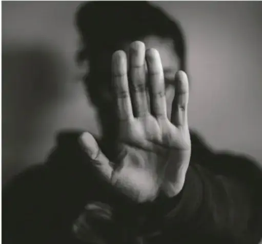 Fotografía en blanco y negro de una persona levantando la mano en gesto de detención, simbolizando el rechazo a la violencia.
