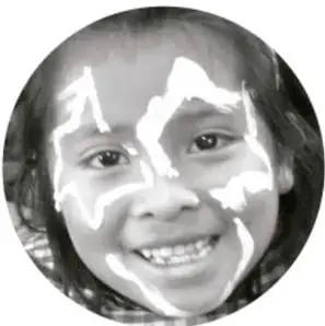 Niña sonriente con pintura facial blanca.