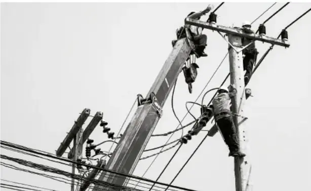 Fotografía en blanco y negro de obreros trabajando en postes eléctricos