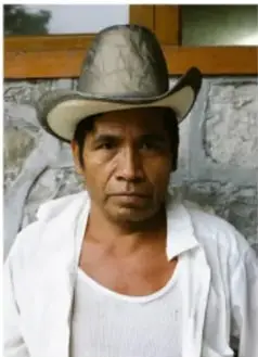 Joven de camiseta verde frente a un muro de ladrillo, desde la cintura a la cabeza, plano medio.