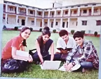 Grupo de estudiantes reunidos en el césped, utilizando computadoras portátiles para trabajar colaborativamente.