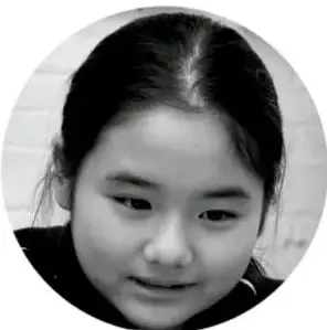 Fotografía de una niña con cabello recogido, mirando hacia abajo.