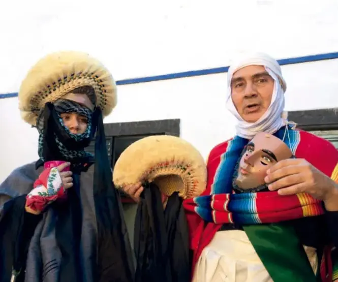Fotografía de personas con vestimenta tradicional, tocados de pelaje y máscaras, representando marcadores culturales de identidad de pueblos indígenas o nómadas.