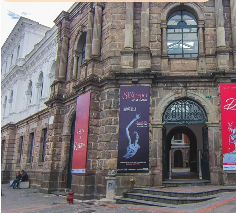 Fotografía de la fachada del Centro Cultural Metropolitano de Quito, un edificio histórico de piedra con columnas, arcos y carteles culturales.