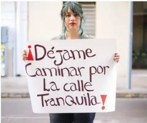 Joven sostiene un cartel que dice: '¡Déjame caminar por la calle tranquila!'