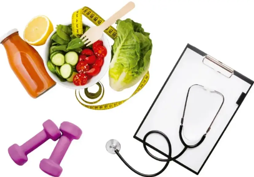 Composición de una vida saludable: ensalada con jitomate, pepino y lechuga, un vaso de jugo, medio limón, una cinta métrica, dos mancuernas moradas, un estetoscopio y un portapapeles con pinza.