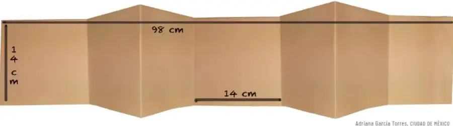 Ilustración de un libro acordeón desplegado de color café claro, con medidas señaladas: 14 cm de ancho, 98 cm de largo y 14 cm por sección. Se observan los dobleces en zigzag que forman siete secciones cuadradas.