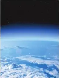 Fotografía de la Tierra vista desde el espacio, donde se observa una capa delgada de gases alrededor del planeta.
