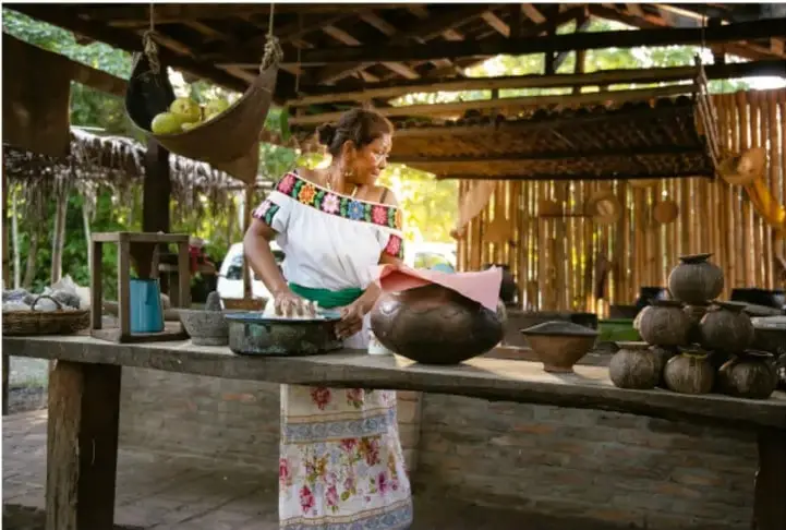 Mujer elaborando vasijas de barro en un taller artesanal.