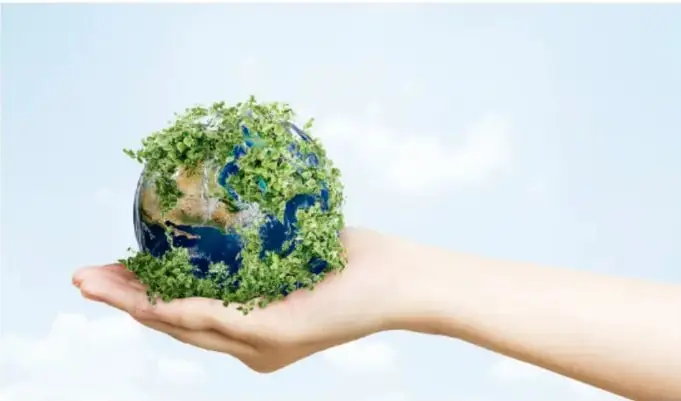 Ilustración de una mano sosteniendo un globo terráqueo cubierto de vegetación, sobre un fondo de cielo con nubes.