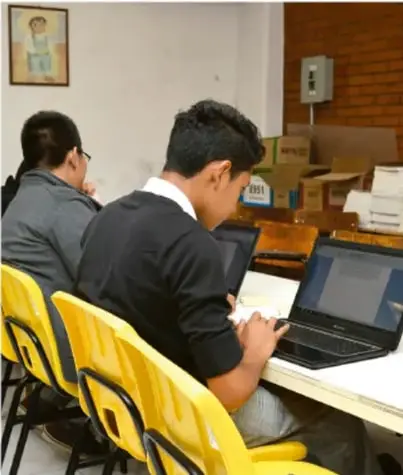 Fotografía de estudiantes trabajando con computadoras portátiles en aula, desarrollando actividades del proyecto.