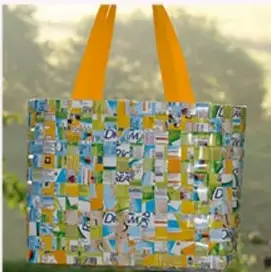 Bolsa de tela hecha con materiales reusados (etiquetas de distintos productos), con asas amarillas, como ejemplo de reúso.