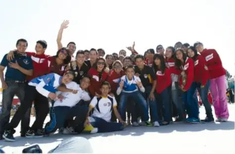 Fotografía de un numeroso grupo de estudiantes en excursión con playeras rojas y de otros colores posando en fila al aire libre. Crédito: Gimenna Schiaffini Rosales, Puebla.